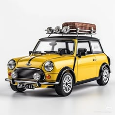 a small yellow car with a surfboard on the top of it's roof