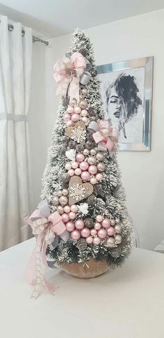 a decorated christmas tree sitting on top of a white table next to a framed photo