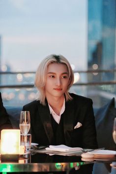 a woman sitting at a table with a wine glass and candle in front of her