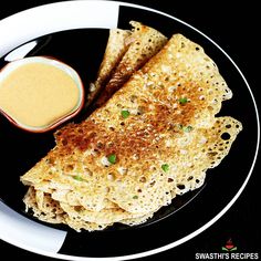 some food is on a black and white plate with a small bowl of dipping sauce