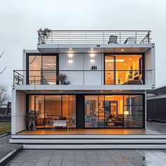 a modern house with glass walls and stairs leading to the upper floor, which also has an outdoor deck