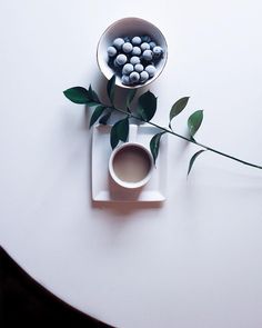 a white table topped with a bowl filled with chocolates and a cup of coffee