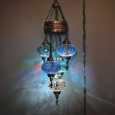 a chandelier hanging from the ceiling with three lights on it and one light turned on