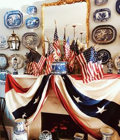 an american flag draped over a fireplace with plates and vases on the wall behind it