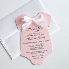 a pink and white baby shower with a bow on it's neck, in front of an envelope