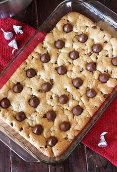 a chocolate chip cookie in a glass baking dish on a red towel and wooden table