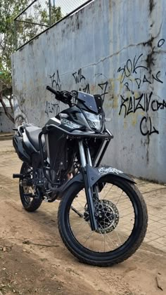 a motorcycle parked next to a wall with graffiti on it