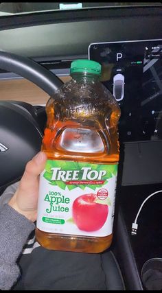 a hand holding a bottle of apple juice