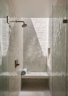 a walk in shower sitting next to a white tiled wall and counter top under a skylight