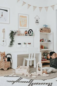 a young child sitting on the floor in front of a white desk and bookshelf