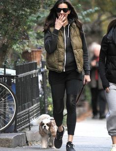 a woman is walking her dog while talking on the phone and holding her hand up to her mouth