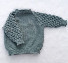 a knitted sweater sitting on top of snow covered ground in the middle of winter