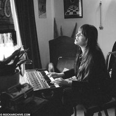 a woman sitting at a piano in front of a window