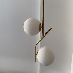 two white balls are hanging from a brass fixture in a room with white walls and flooring