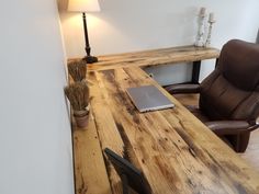 a laptop computer sitting on top of a wooden desk next to a brown leather chair