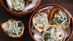 four small bowls filled with food on top of a wooden table next to some bread