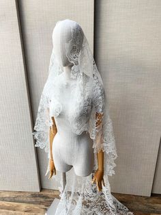 a mannequin wearing a white wedding dress and veil on top of a wooden table