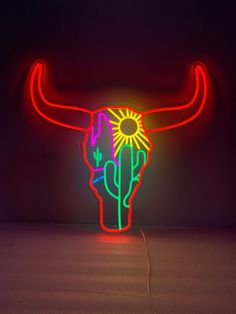 a neon sign with a bull's head and cactus on it in the dark