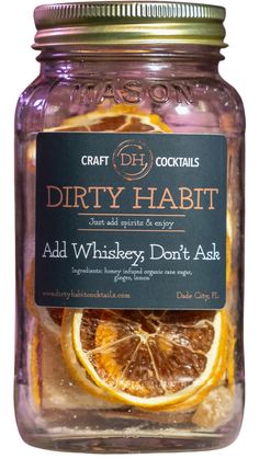 a glass jar filled with oranges and lemon slices next to a label that says dirty habitt