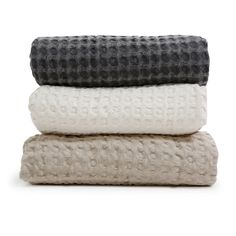 three blankets stacked on top of each other in different colors and patterns, one black and white