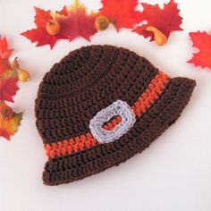 a crocheted hat with an o on it and autumn leaves around the cap