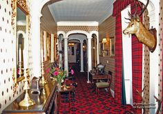 the hallway is decorated in red and gold with deer heads mounted on the wall above it