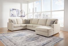 a living room with a sectional couch and rug in front of large windows overlooking the city