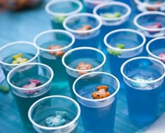 plastic cups filled with different types of food on top of a blue table covered in candy