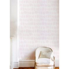 a white chair sitting in front of a wall with pink and white designs on it