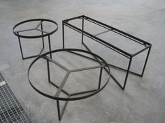 three metal tables sitting on top of a cement floor