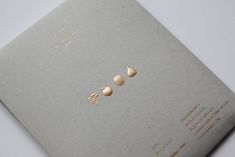 three gold studs are placed on the back of a gray book with white writing