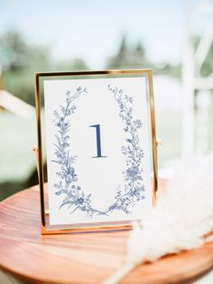 a table with a card on it that has a number one in the middle and some feathers next to it