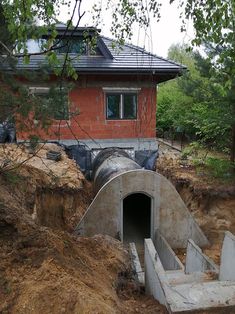 a large pipe is in the ground next to a house that has been built into it