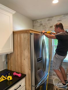 a man is using a power tool to clean the refrigerator