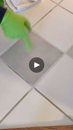 a person in green gloves cleaning a tile floor