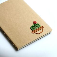 a notebook with a cactus embroidered on the cover