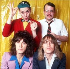 three men are posing for a photo in front of a yellow backdrop and one man is wearing a tie