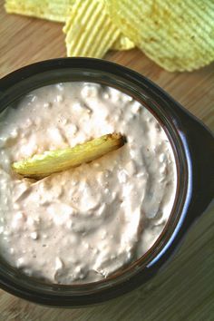 a banana sticking out of the top of a bowl of dip with chips on the side