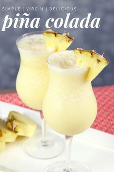 two glasses filled with pineapple drink sitting on top of a white plate