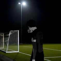 a man standing in front of a soccer goal on a field at night with his hand to his face