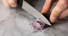 a person cutting up food with a large knife on top of a marble countertop