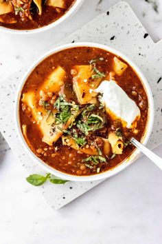 two bowls of tortilla soup with sour cream and spinach on the side