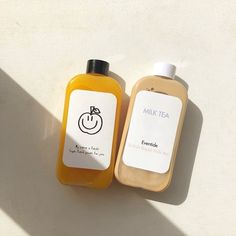 two bottles of juice sitting next to each other on a white surface with shadows from the sun