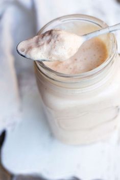 a spoon full of orange juice on top of a glass jar with liquid in it