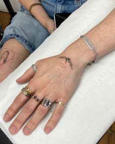 two people with tattoos on their hands sitting next to each other and one is holding the other's hand