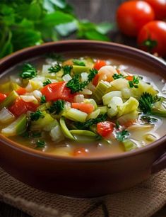 a brown bowl filled with soup next to tomatoes and broccoli