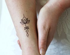 a woman with a tattoo on her arm holding the hand of another person's wrist