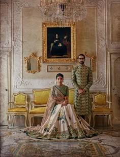 a man and woman standing next to each other in front of a painting on the wall