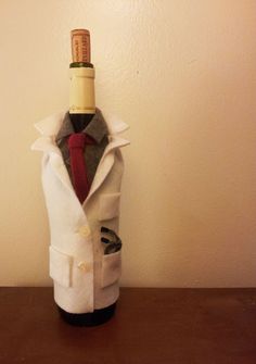 a wine bottle with a white coat and red tie on it sitting on a table