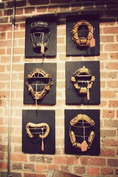 four baseball catcher's mitts hanging on the wall next to a brick wall